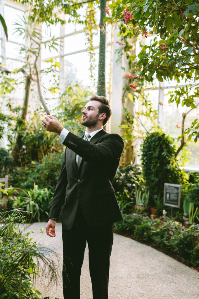 Groom holding out a hand to catch a butterfly on his finger
