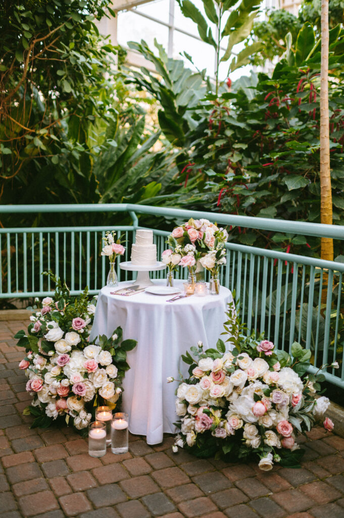 Wedding cake table surrounded by pink and white florals
