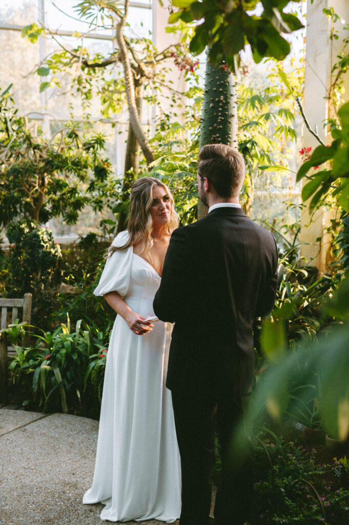 Bride reading her vows to groom during greenhouse elopement ceremony