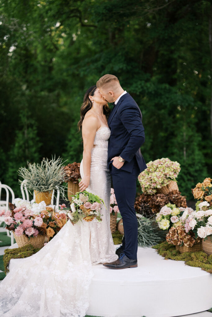 bride and groom kissing at the outdoor ceremony space at greenhouse at arrows farm