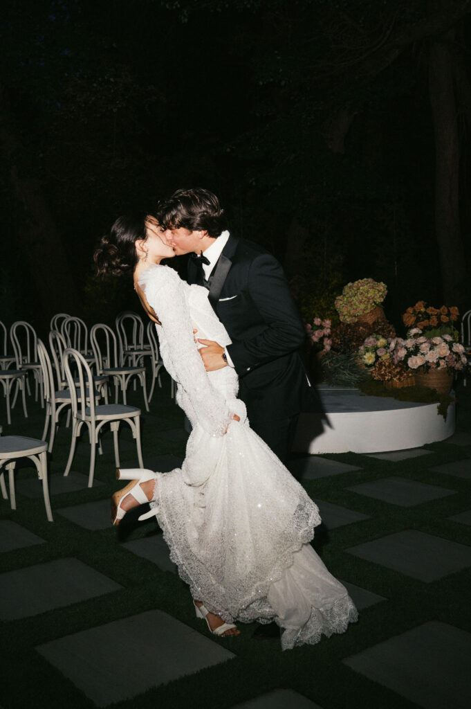 editorial style flash photos of bride and groom kissing at the outdoor ceremony space at greenhouse at arrows farm